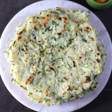 healthy and savory zucchini pancakes served on white marble plate.