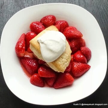 best strawberry shortcake in serving plate layered with biscuits, strawberries and whipped cream.