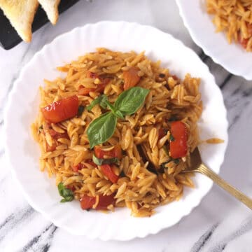 quick and easy orzo pasta on serving plate with tomatoes and basil.