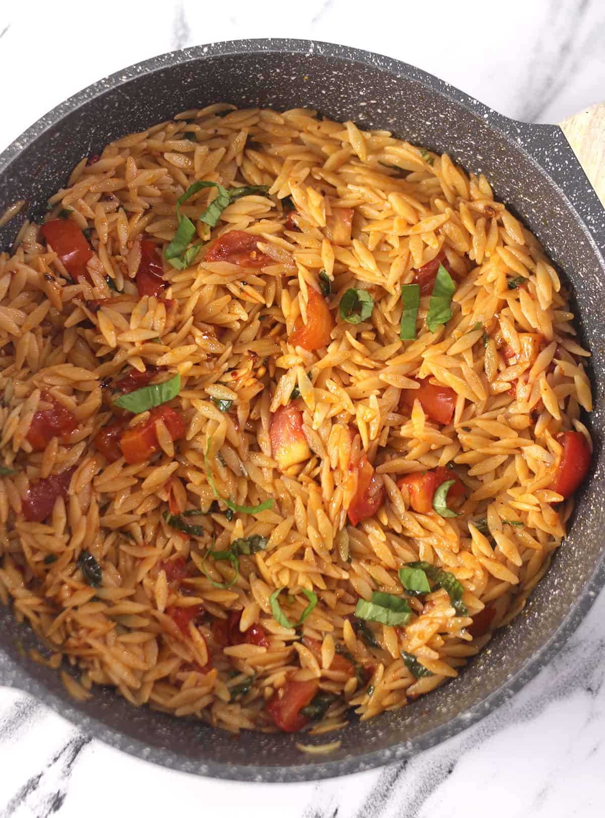 Warm orzo pasta salad in a black nonstick pan. 