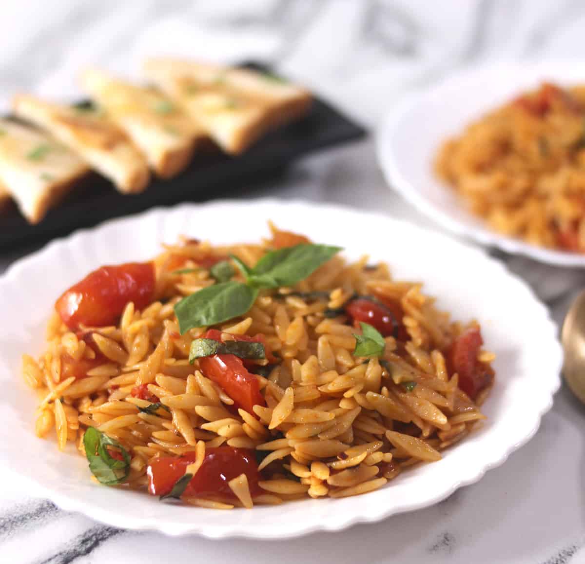 Best and quick orzo with fresh basil and tomatoes in a white serving plate. 