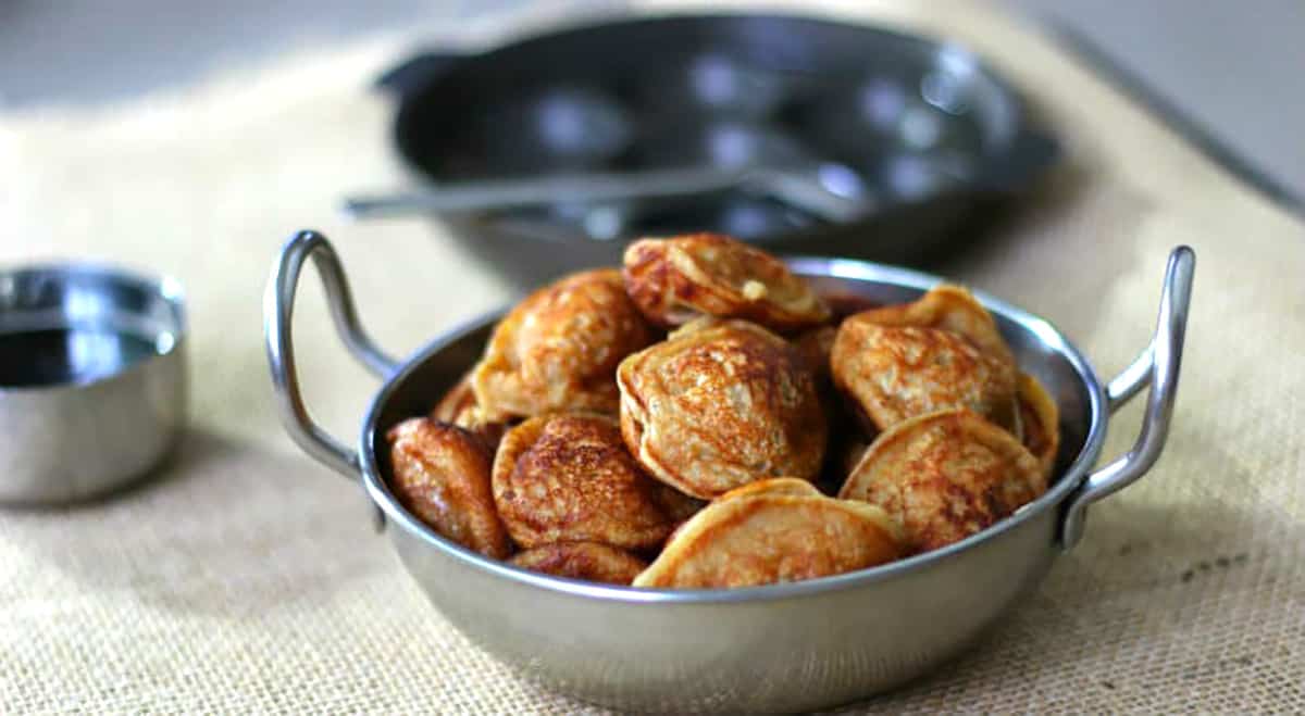 Sweet appam or paniyaram in a pan made with wheat flour, ripe bananas, and jaggery - Indian snack. 