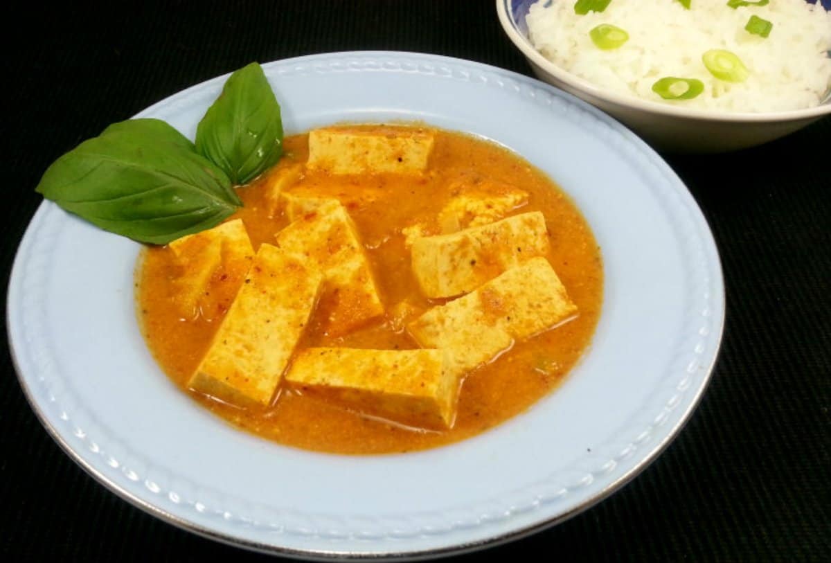 Easy and Tasty Red Curry Stir Fry with Tofu served in a white ceramic dish and served with steaming hot jasmine rice.