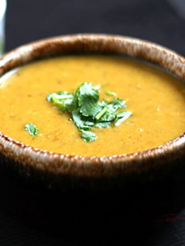 Best and easy lentil soup on serving bowl garnished with cilantro.
