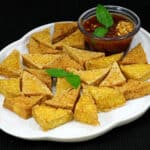 Crispy fried tofu with sweet and spicy Thai peanut sauce on a white plate.