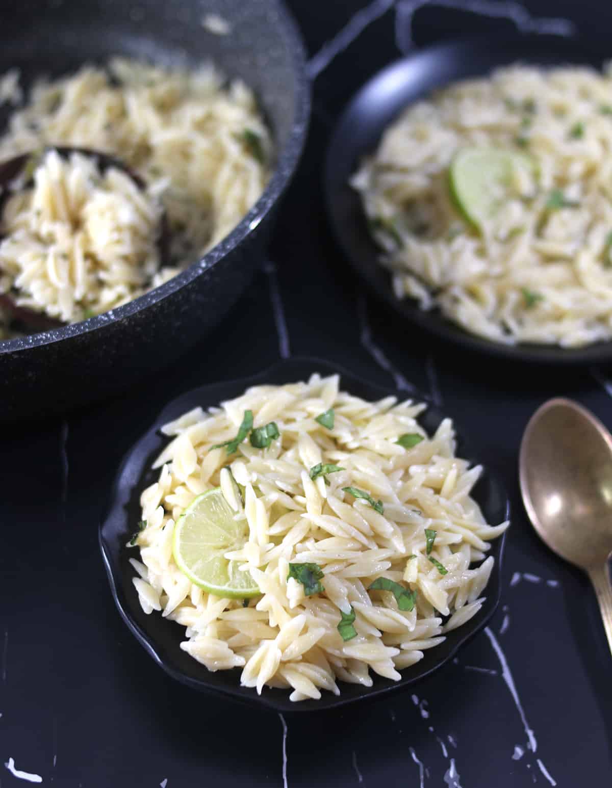 Best one pot lemon orzo pasta served on black plate with golden spoon.