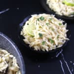Best and easy lemon orzo pasta salad in a black bowl garnished with fresh basil.