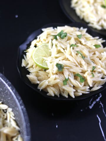 Best and easy lemon orzo pasta salad in a black bowl garnished with fresh basil.