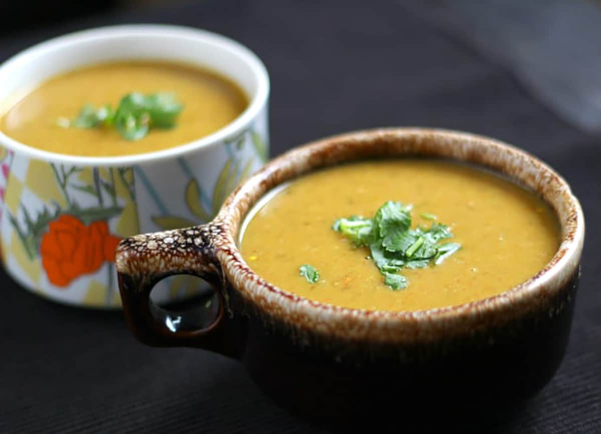 healthy high protein dal soup in 2 serving bowls garnished with cilantro. 