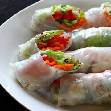 Fresh spring rolls (summer rolls) in a white serving plate with peanut dipping sauce.