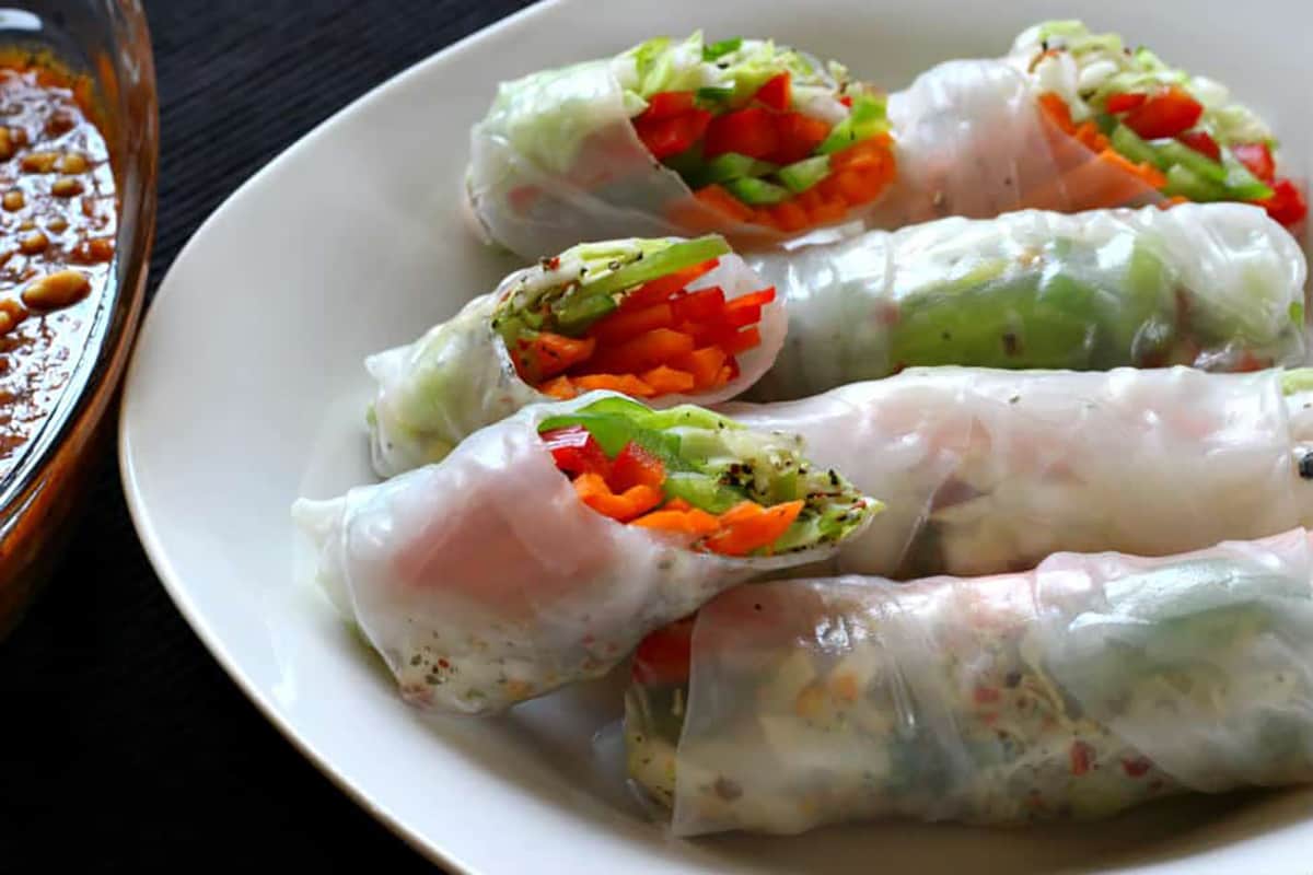 Fresh Vietnamese spring rolls in serving plate with peanut dipping sauce. 