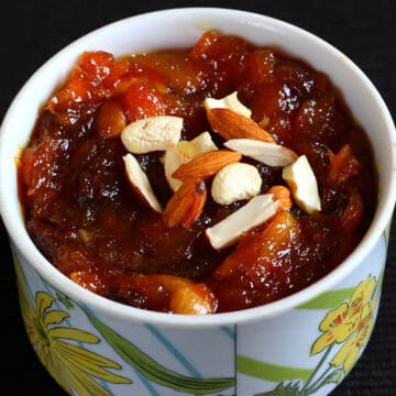 best peach mango halwa Indian sweet dessert in a white bowl garnished with nuts.