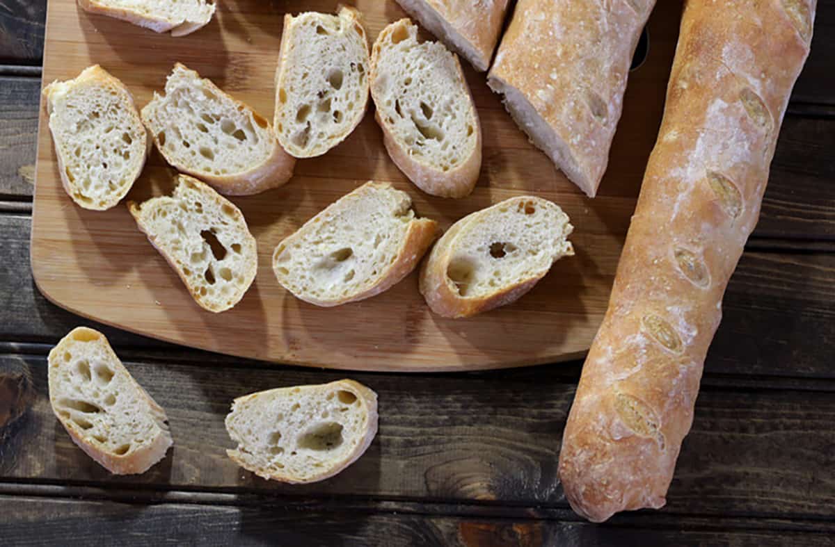 Easy Homemade No Knead baguette loaves and slices on serving board. 