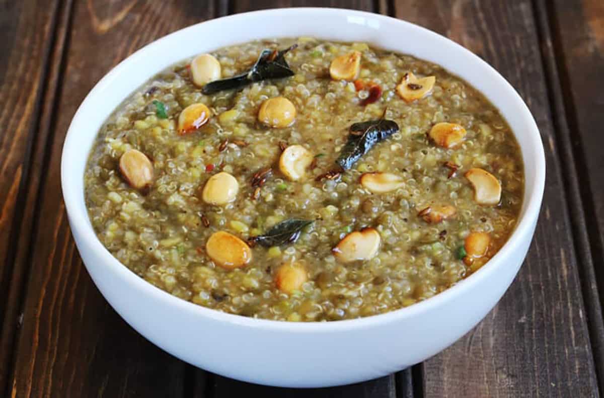 healthy south indian quinoa pongal garnished with roasted cashews and served in white bowl.