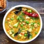 One pot bisi bele bath or masala khichdi in a white serving bowl with tempering.