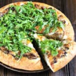Homemade pizza crust topped with mushrooms, caramelized onions, fresh arugula and cheese.