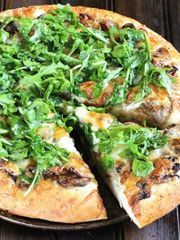 Homemade pizza crust topped with mushrooms, caramelized onions, fresh arugula and cheese.