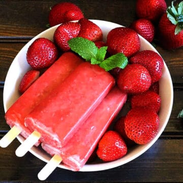 Best homemade strawberry popsicles with fresh strawberries in a serving bowl.