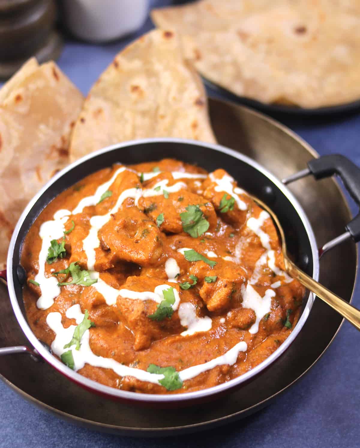 Creamy chicken makhani, butter chicken curry sauce drizzled with cream and served with Indian bread.