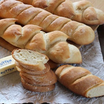 Authentic and best French baguette loaves with stack of crusty slices and butter.