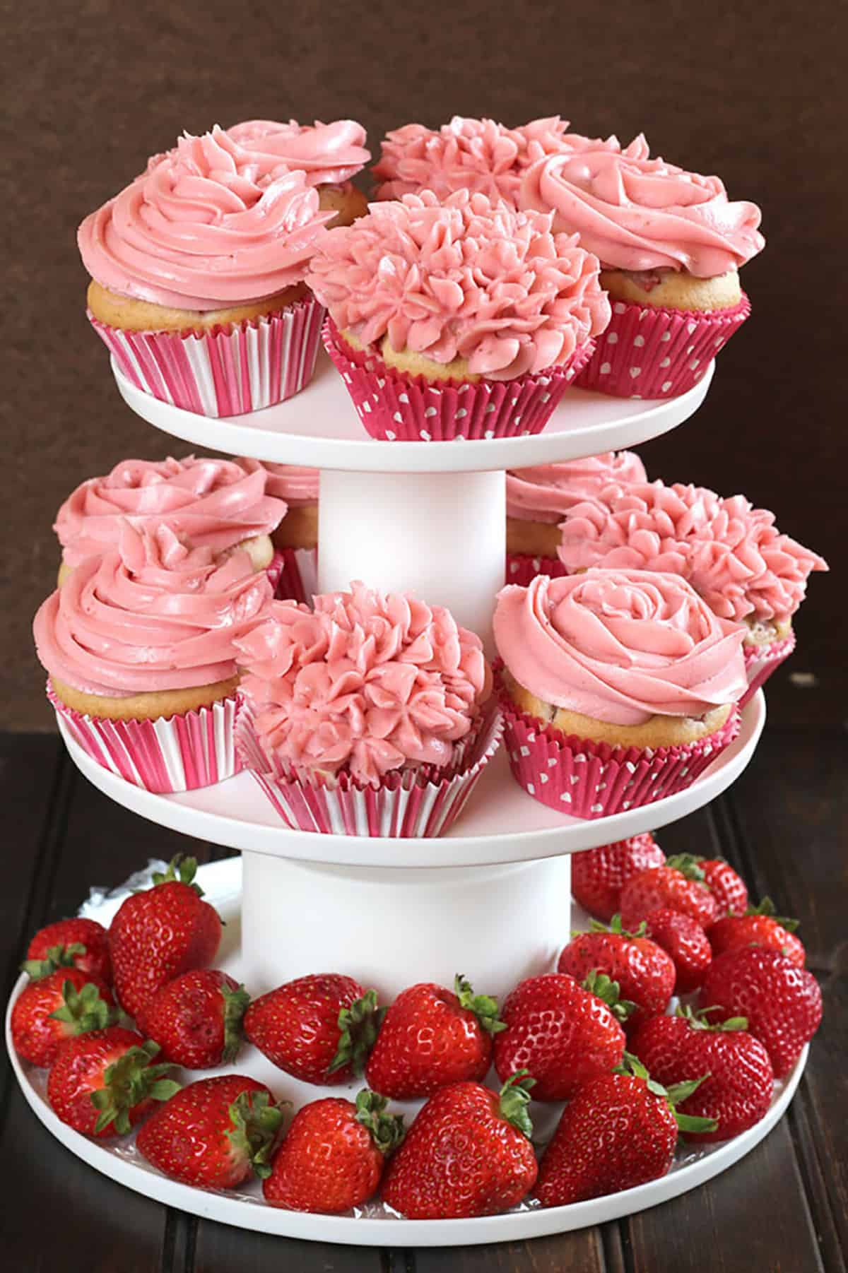 12 strawberry cupcakes beautifully decorated with frosting and arranged with fresh strawberries 