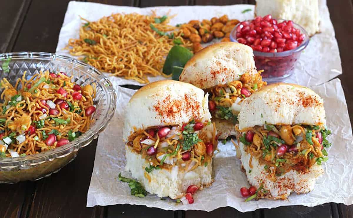 Indian kacchi dabeli street food with a bowl of dabeli masala mixture and garnish.