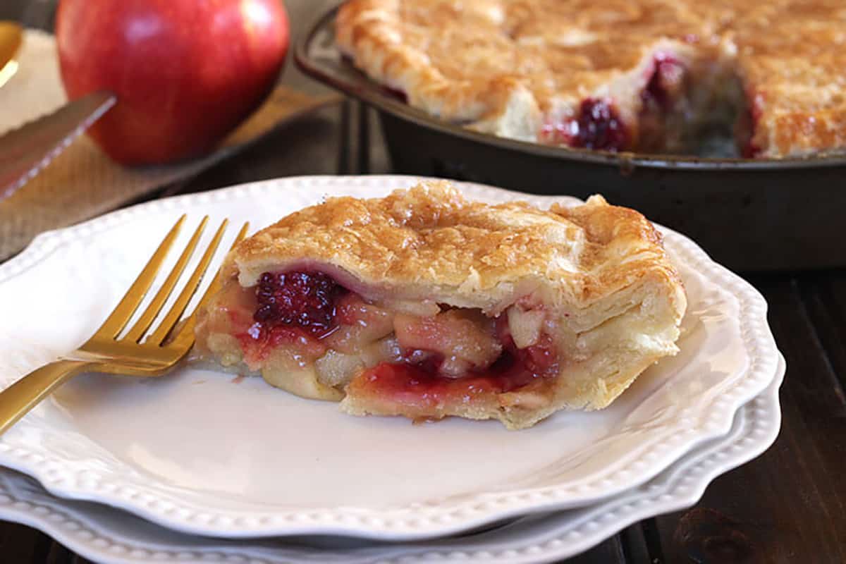 Slice of homemade flaky, best and easy blackberry apple pie in a serving plate. 