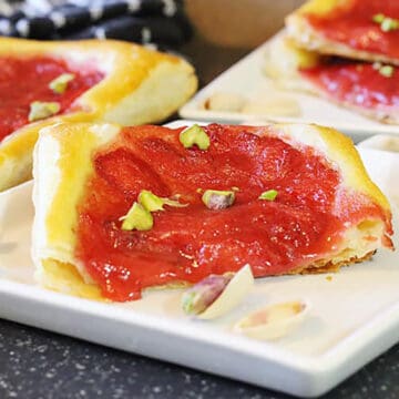 strawberry tarts dessert prepared with compote filling & puff pastry base in a white serving plate.