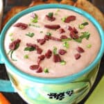 Cream cheese olive dip (spread) garnished with chopped kalamata olives and fresh herbs.