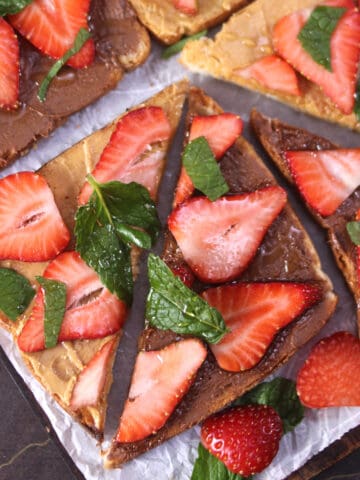 Strawberry toast topped with peanut butter and Nutella, garnished with mint leaves.