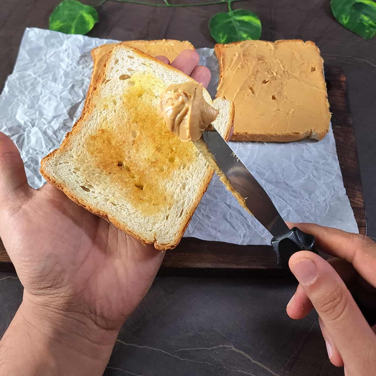 Spread peanut butter on top of toasted bread using a butter knife.