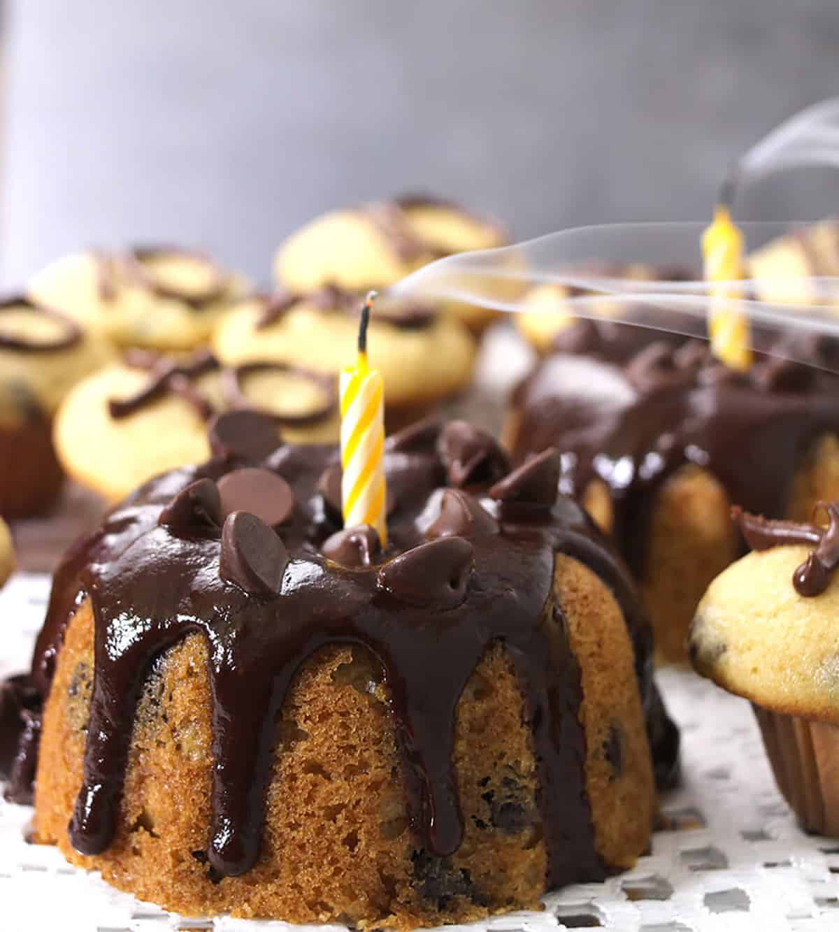 mini chocolate chip bundt cake and cupcakes with chocolate ganache and candle on top. 