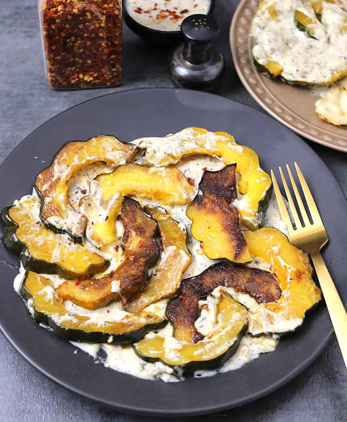savory caramelized acorn squash served on a plate with garlic cream sauce. 