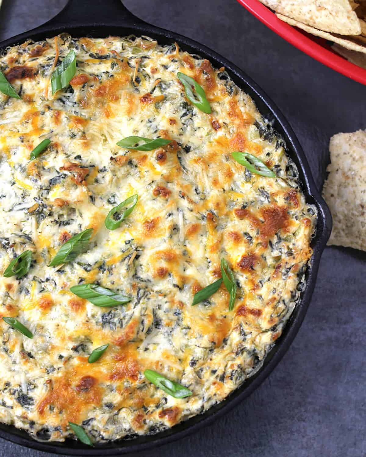 Baked hot spinach artichoke dip in cast iron skillet.