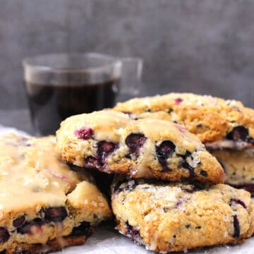 Blueberry scones serve on parchment paper with black coffee in the background.