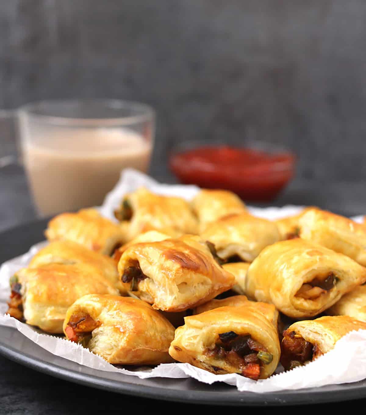 crispy, flaky veg puffs or savory curry puff on a serving plate with tea and ketchup. 