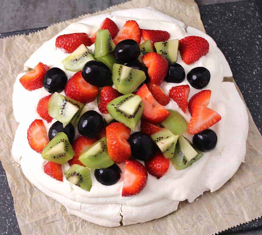 Pavlova - meringue based gluten free cake dessert topped with fresh fruits and homemade whipped cream.