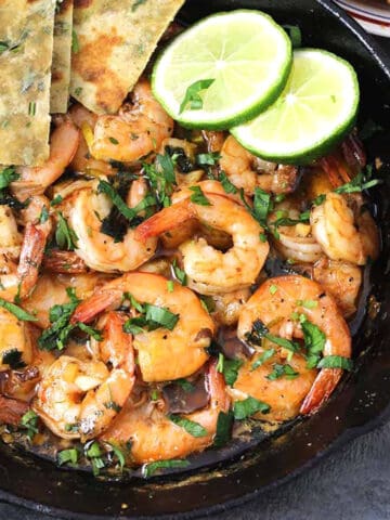 Best garlic butter shrimp recipe (garlic prawns) in a cast iron pan with lemon wedges.