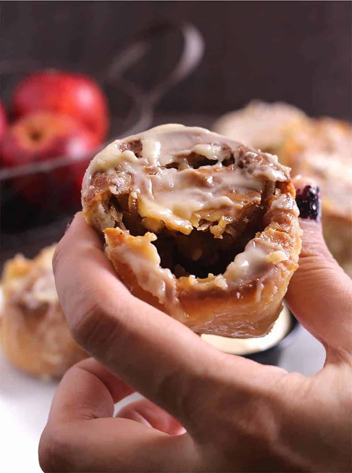 Holding the best homemade cinnamon rolls with the apple pie filling