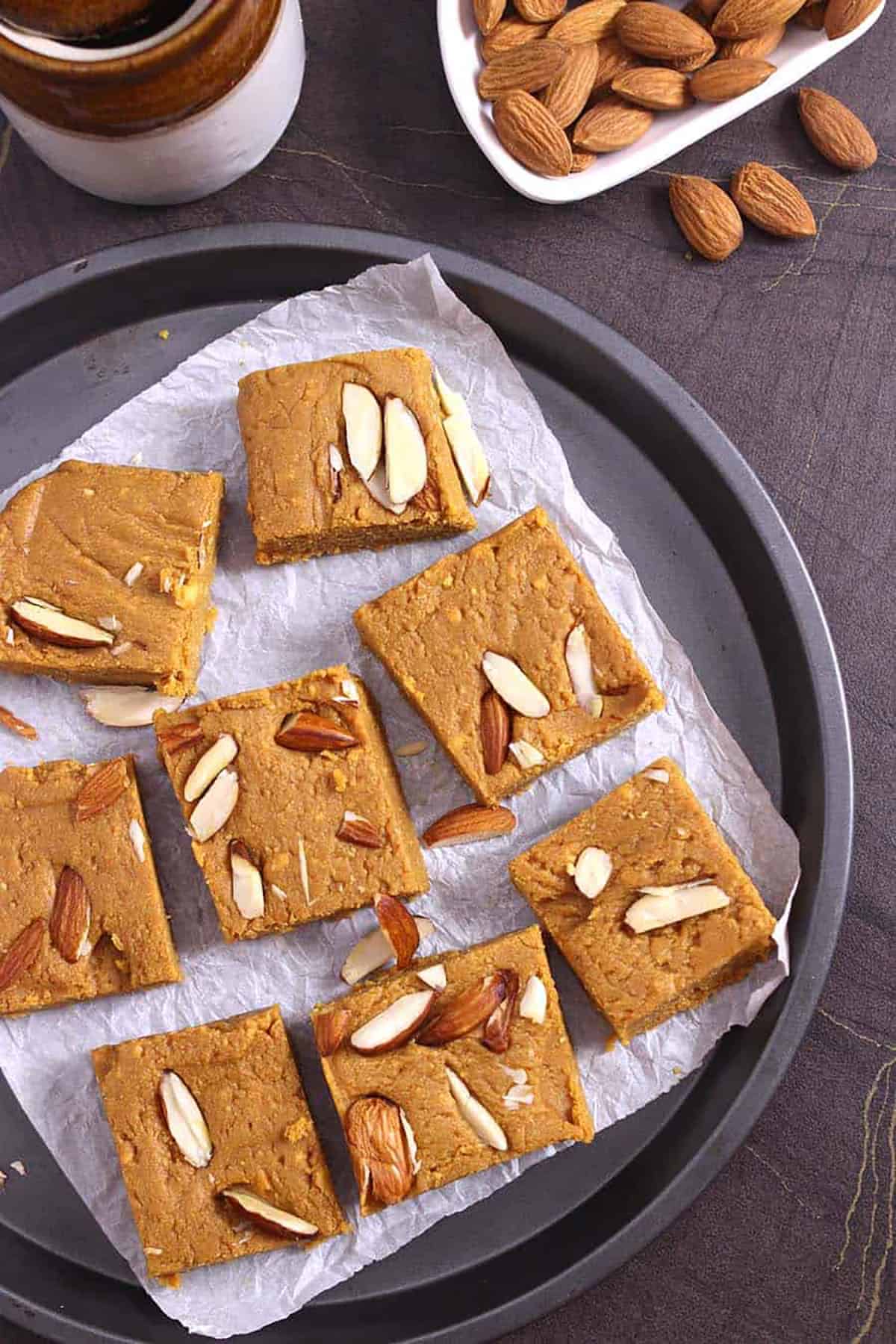 Indian besan burfi bites or besan ki barfi mithai on a plate garnished with almonds. 