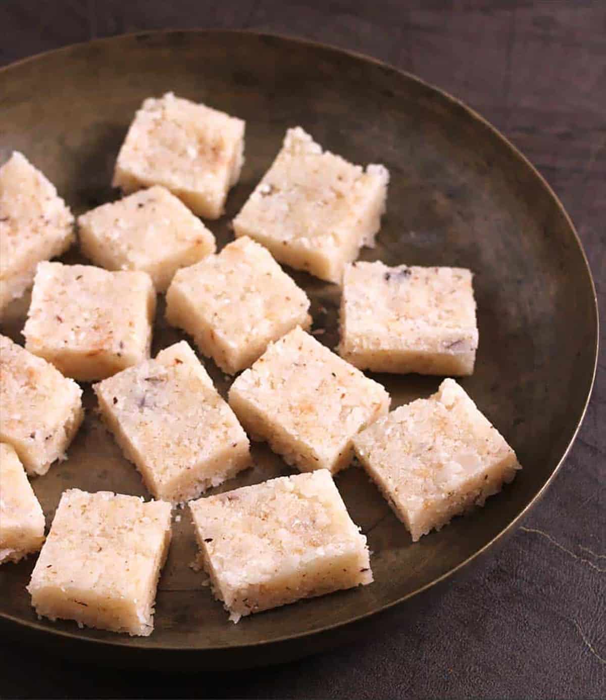 Best Indian coconut burfi sweet (thengai, kobbari or nariyal) mithai bites on a bronze plate. 