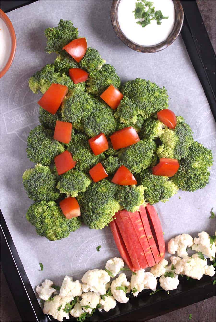 edible christmas tree with vegetables like broccoli, cherry tomatoes, carrot, cauliflower, radish