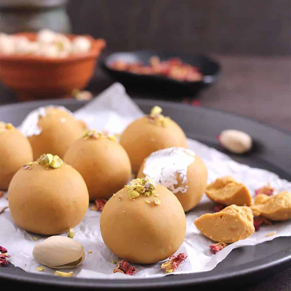 Besan Ladoo garnished with rose petals and crushed pistachios.