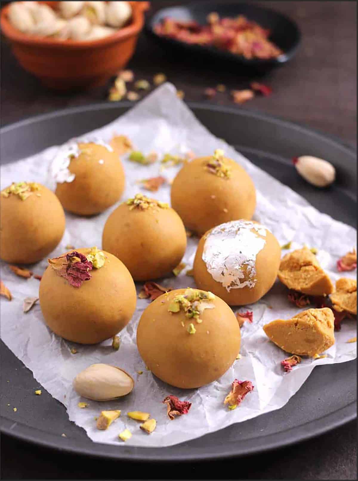 Besan ladoos (bandar laddu) placed in a black plate on a parchment paper.