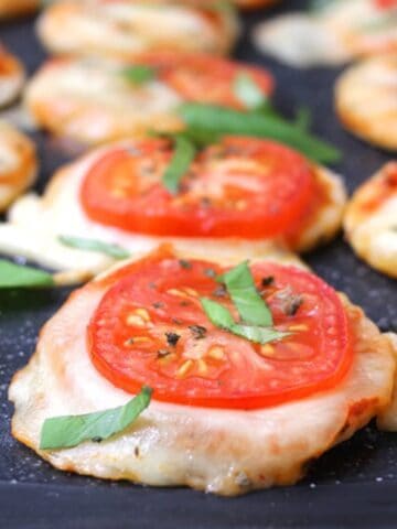 Quick and simple mini pizzas served on a black board.