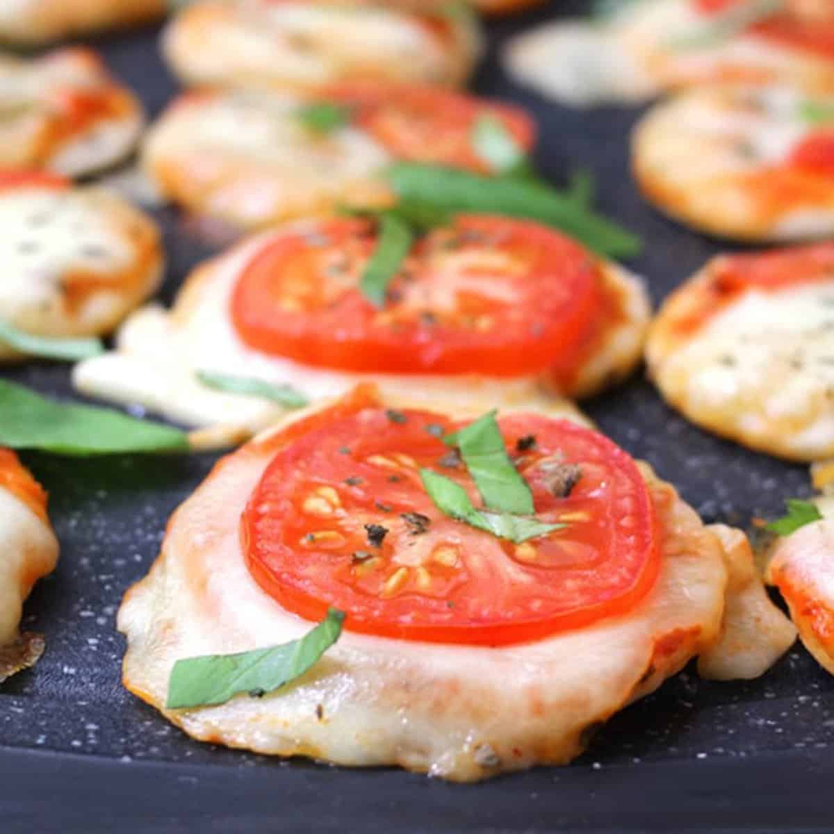 Quick and simple mini pizzas served on a black board.