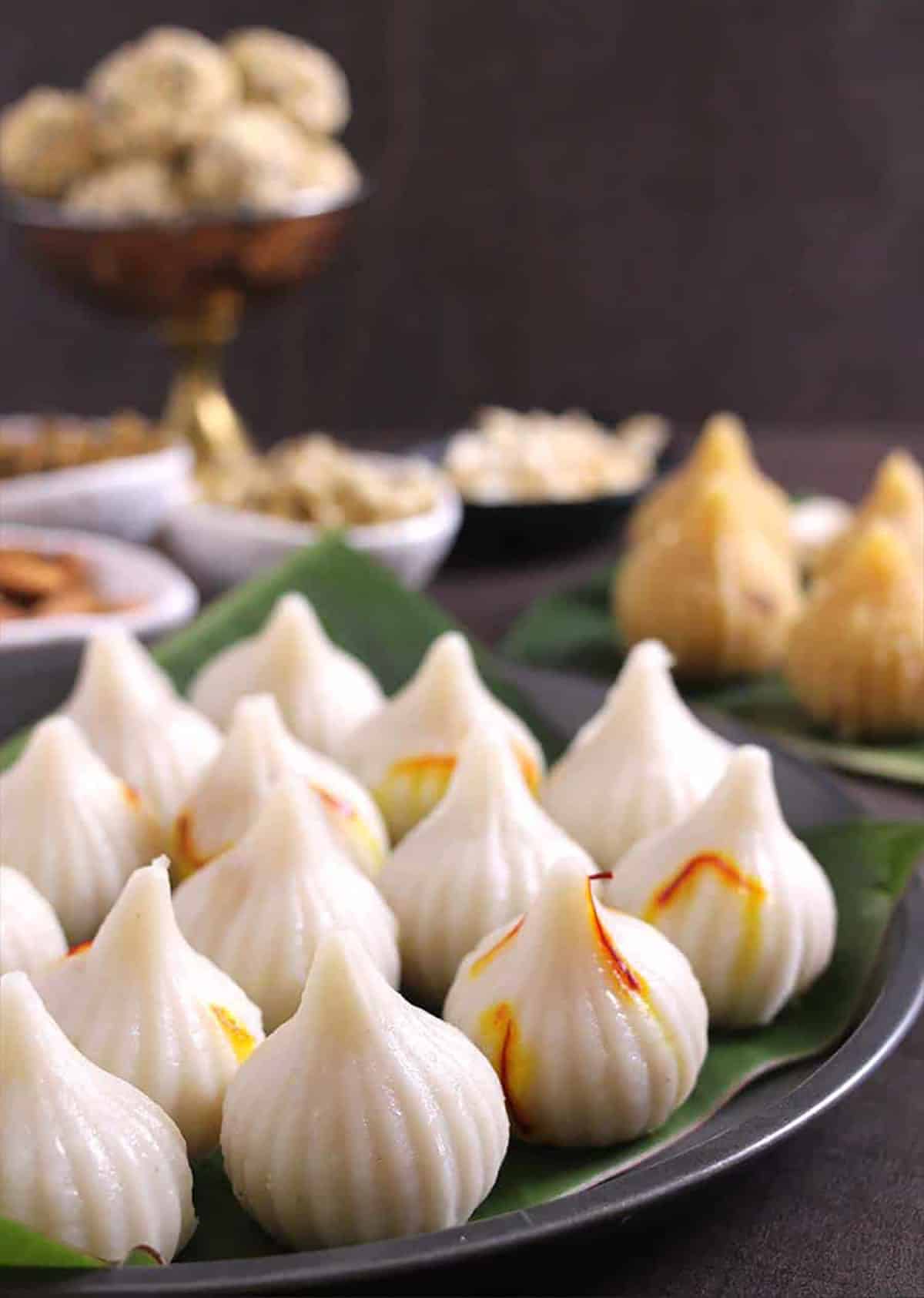 Steamed modak served on a black plate lined with banana leaf.