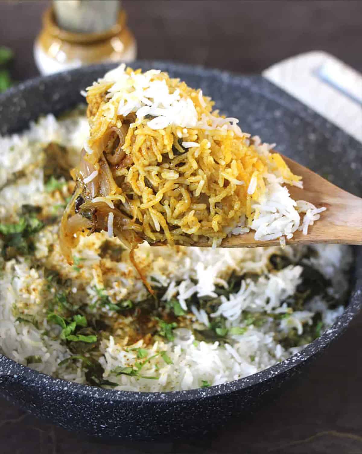 Chicken biryani in a spatula, backround shows the pan or pot in which the biryani was cooked.
