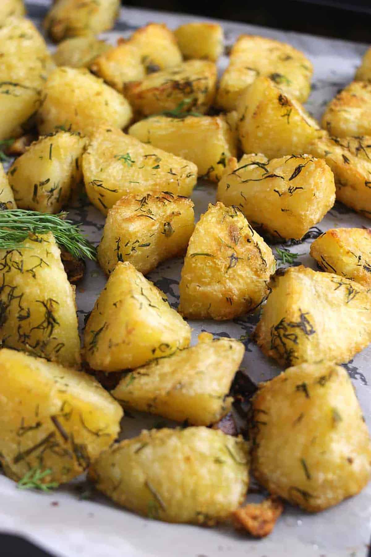 Close up shot of roasted garlic-herb potatoes in a baking pan.