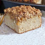 A slice of apple coffee cake served on parchment paper.